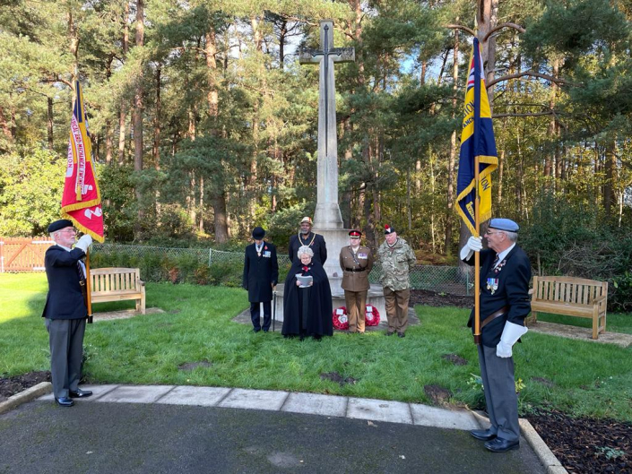 Standard bearer in front of people by war memorial
